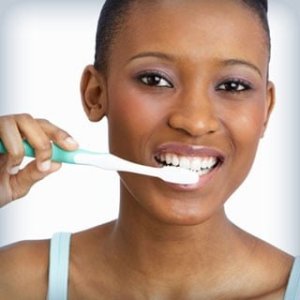 A young woman brushes her teeth using small, gentle strokes